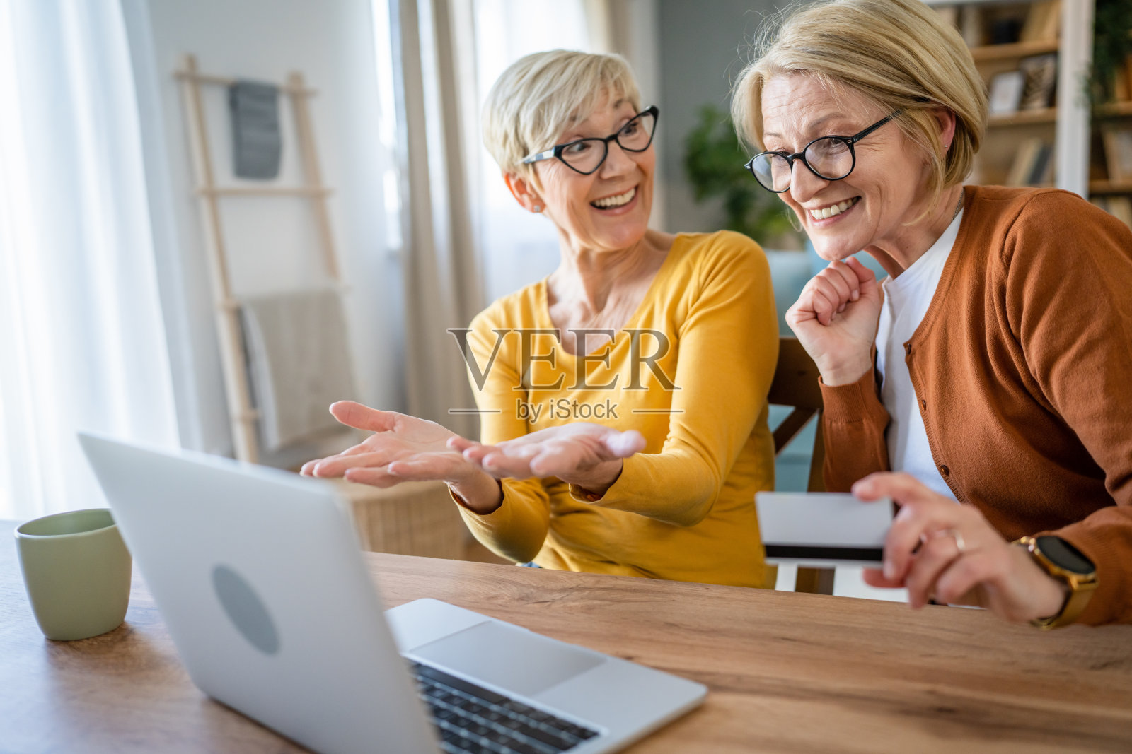 年长的妇女在家中持信用卡进行网上购物照片摄影图片