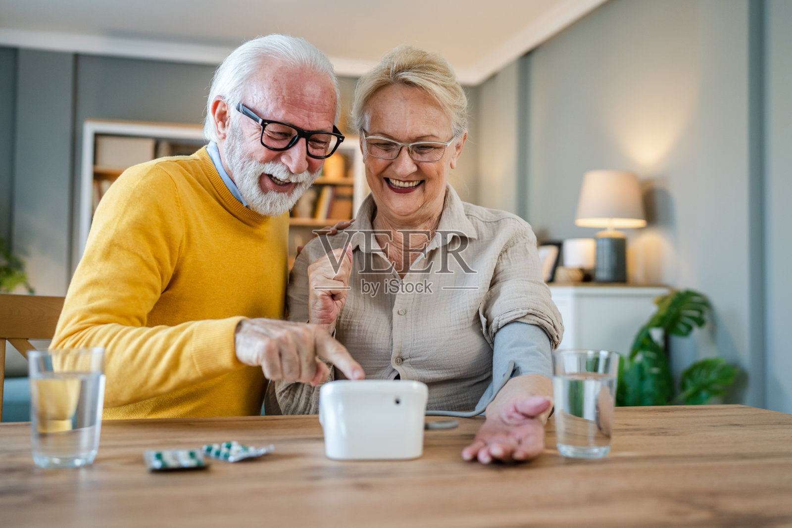 老两口在家，女方量血压，丈夫坐在旁边照片摄影图片