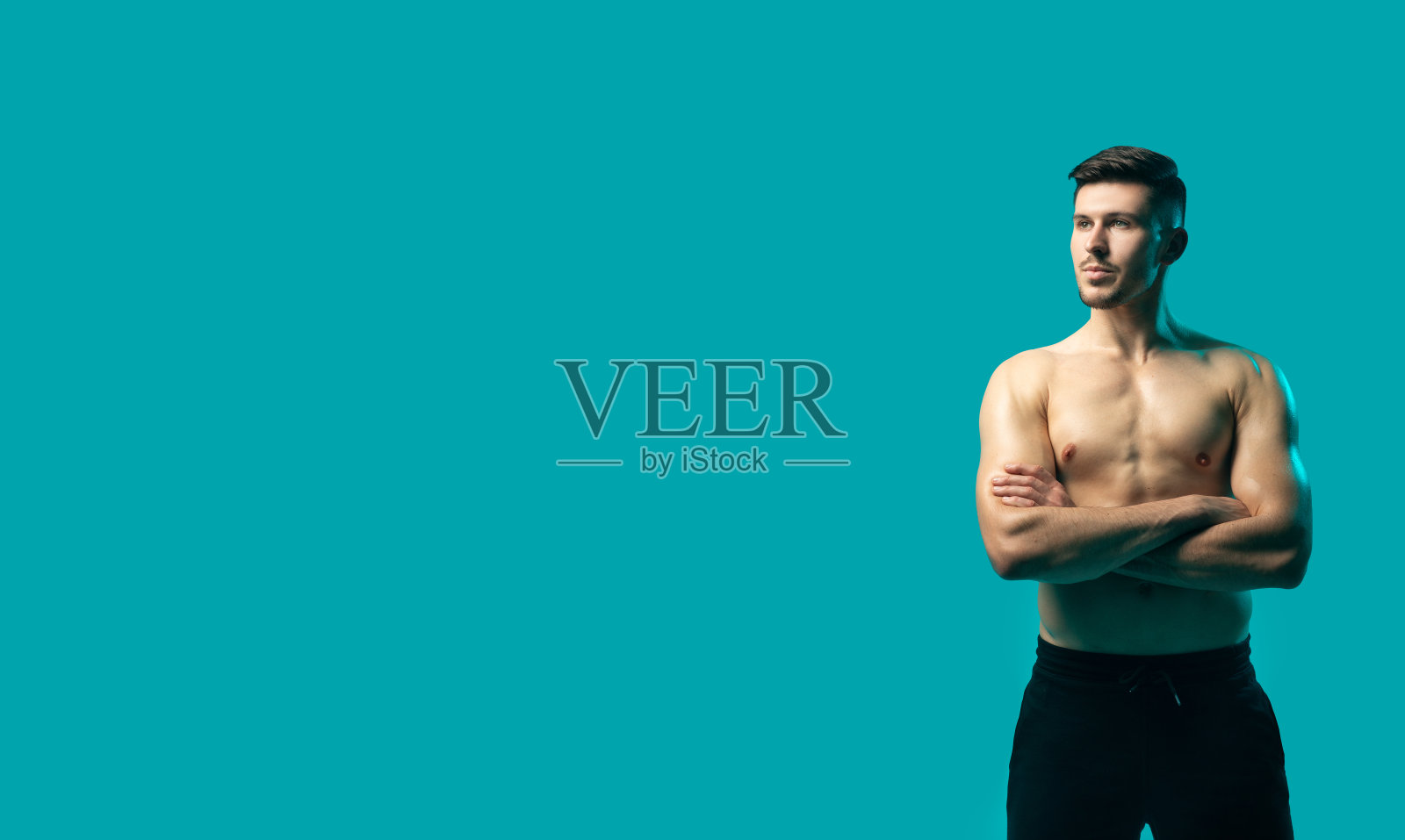 赤膊男子站在绿松石背景前，复制空间照片摄影图片