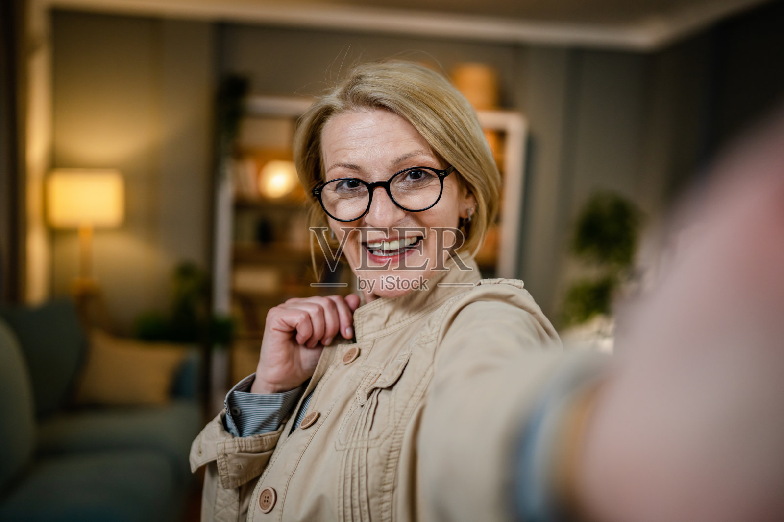 一个成熟的金发白种女人在家里戴着眼镜的肖像照片摄影图片