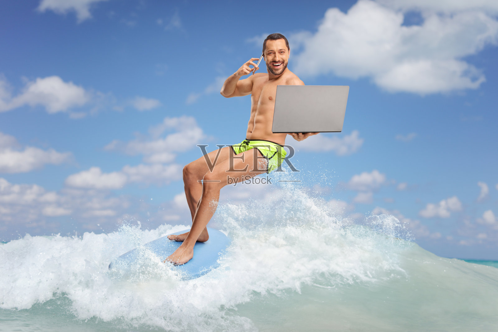 一个人在海里骑着冲浪板，拿着笔记本电脑打电话照片摄影图片