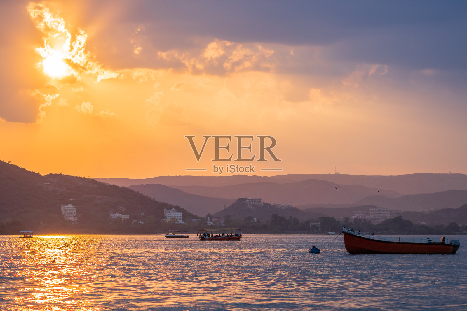 这张照片显示的是印度拉贾斯坦邦乌代普尔的一片水面上的日落，水面上漂浮着船只照片摄影图片