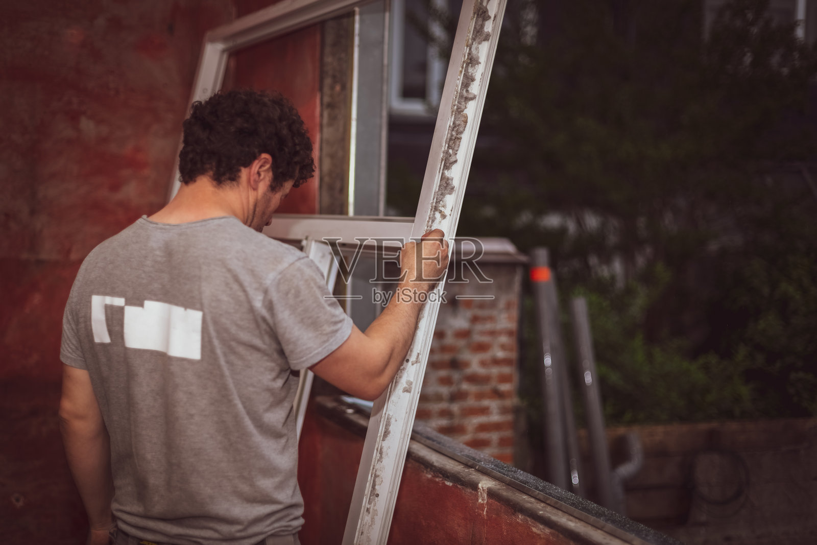 白人男建筑工人检查肮脏的窗框。照片摄影图片