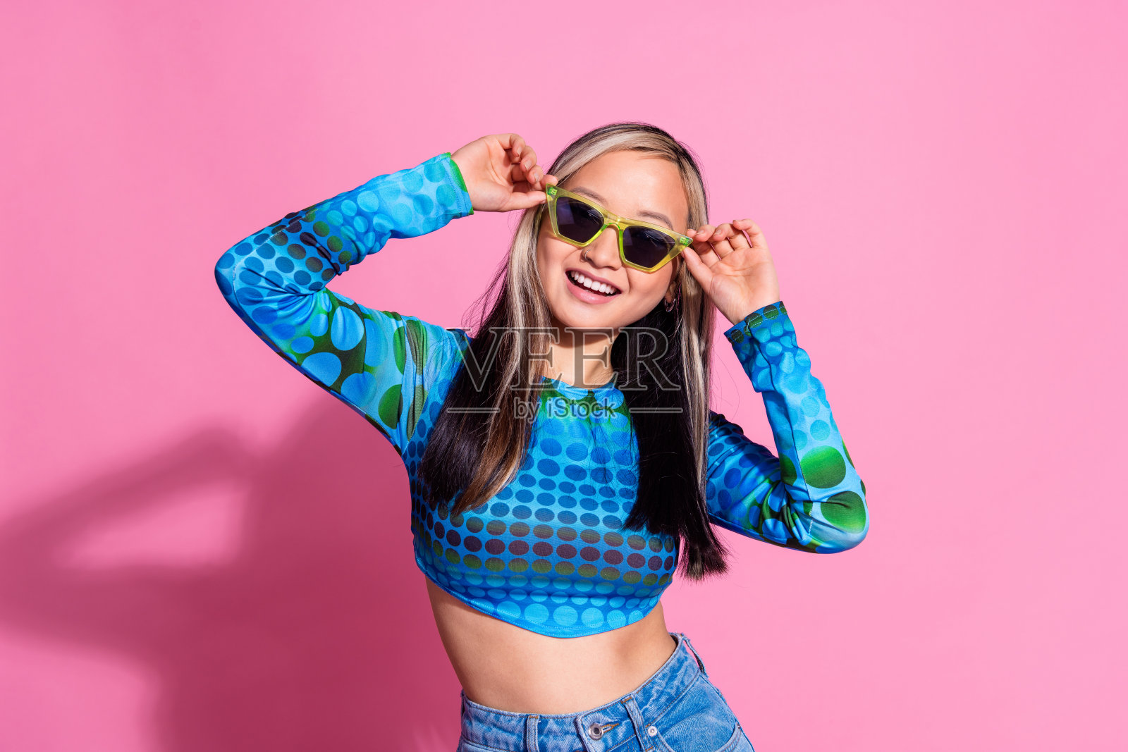 照片中闪亮女士穿着印花衬衫，深色眼镜微笑，空白空间孤立的粉红色背景照片摄影图片