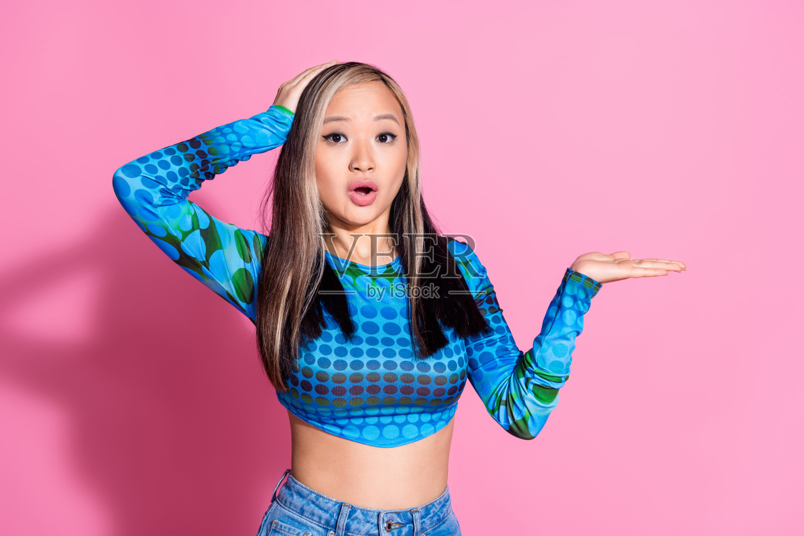 印象深刻的漂亮女士穿着蓝色衬衫，显示手臂空白空间孤立的粉红色背景照片摄影图片