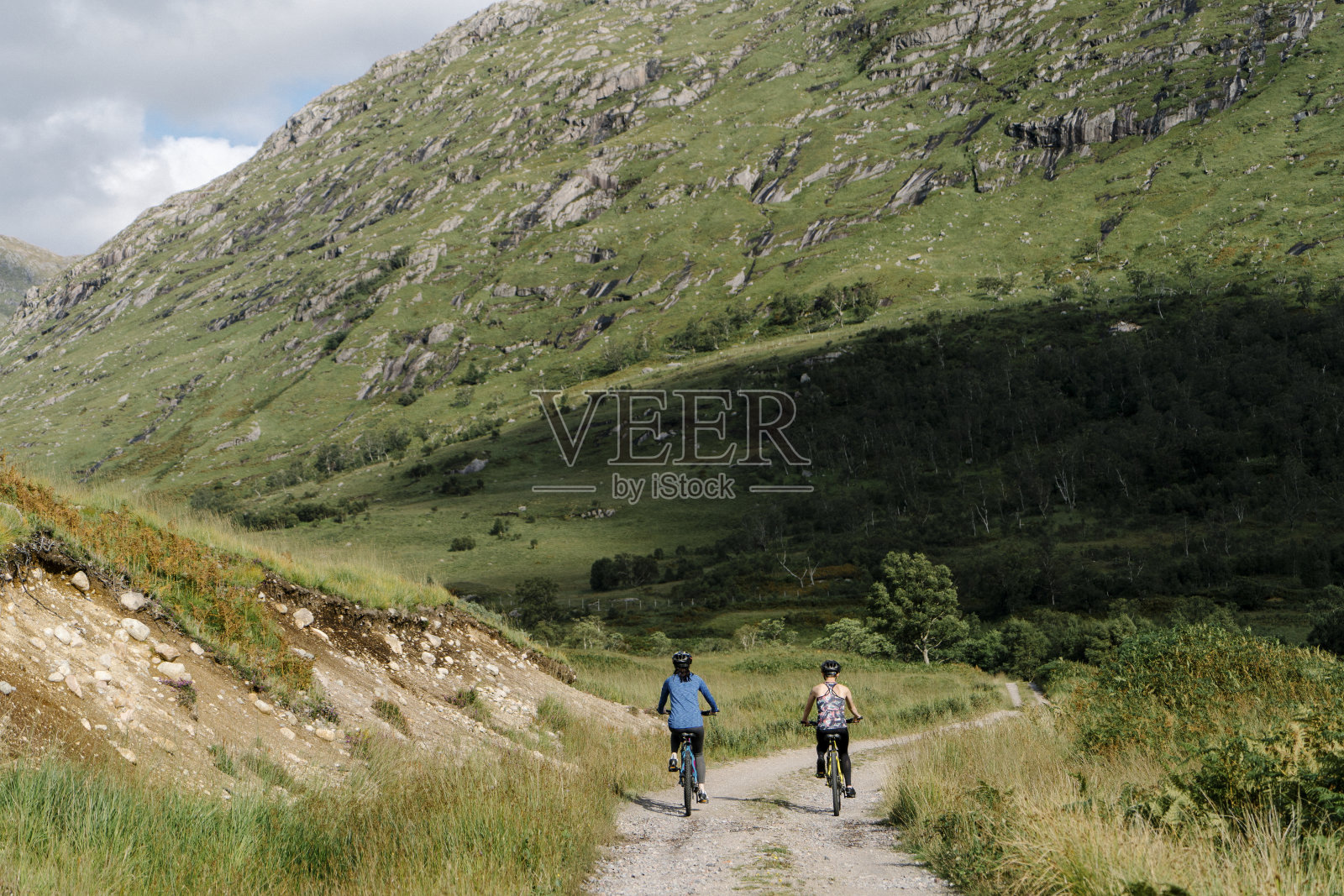 一对夫妇在苏格兰高地的路上骑车照片摄影图片