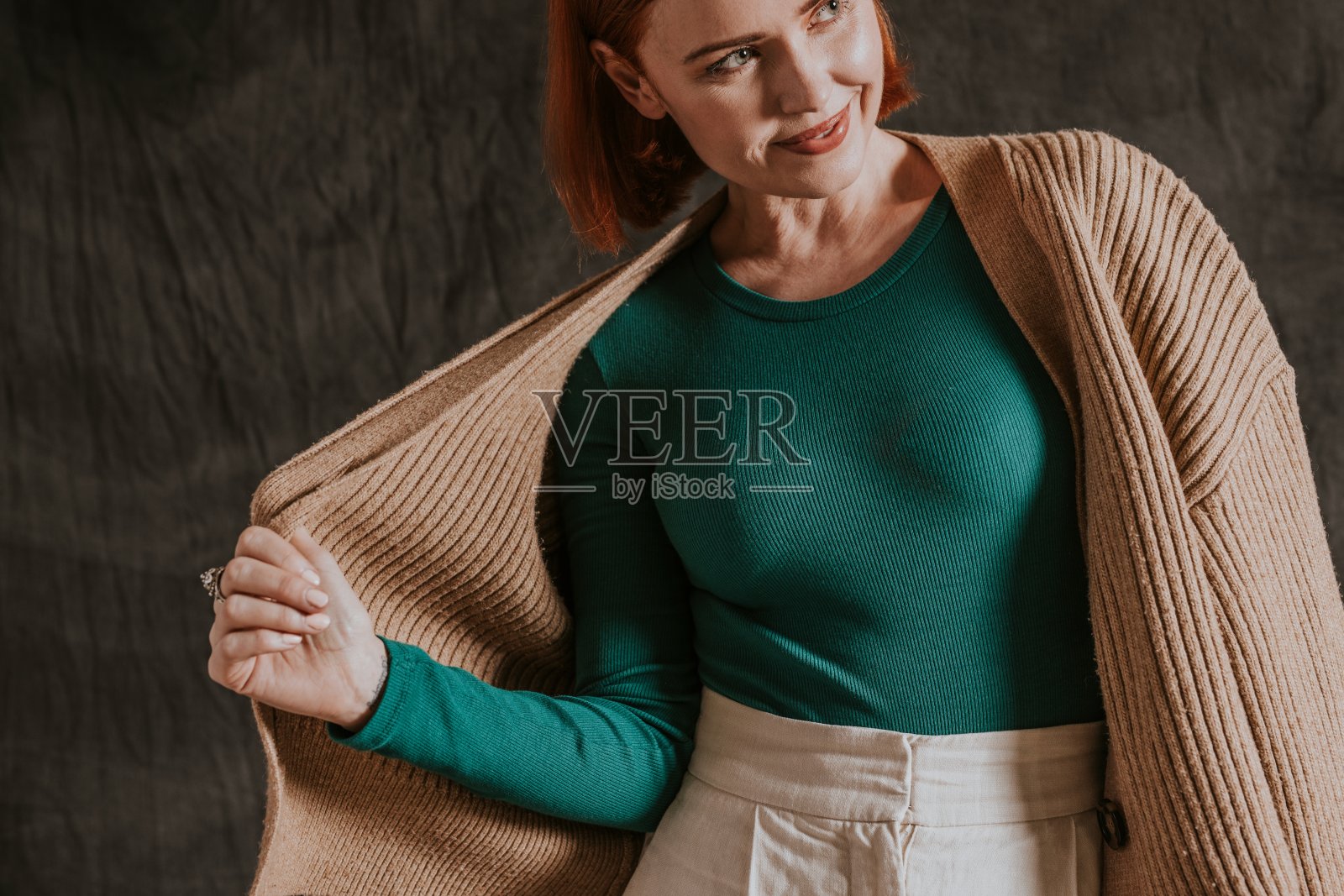 快乐的女人在绿色的长袖上穿上棕色的开襟羊毛衫，秋天的服装时尚设计照片摄影图片
