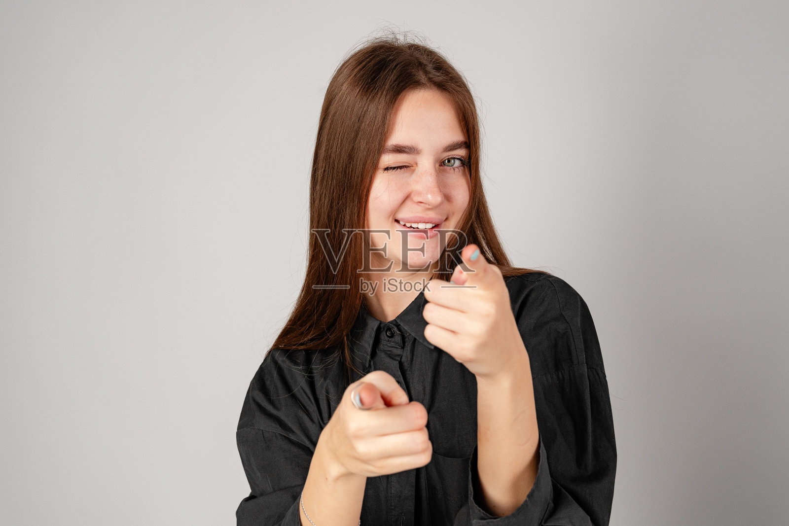 年轻女子在画框里用手做手势，背景平平照片摄影图片