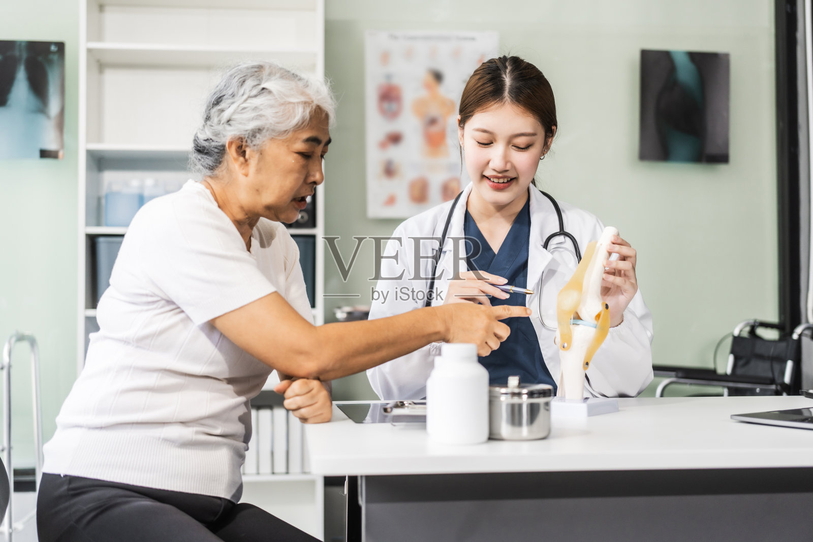 一位年轻的亚洲女护士在她的办公桌上提供医疗服务，照顾一位老年妇女病人。他们在专业的环境中讨论健康清单和医疗建议。照片摄影图片