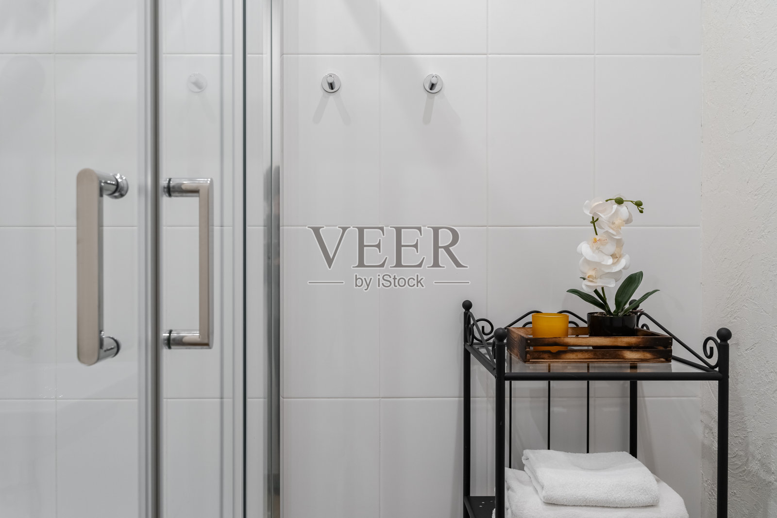 现代的浴室设计，浅色的瓷砖，白色的家具和一个可以看到各种风景的玻璃淋浴房。浴室里的黑色架子照片摄影图片