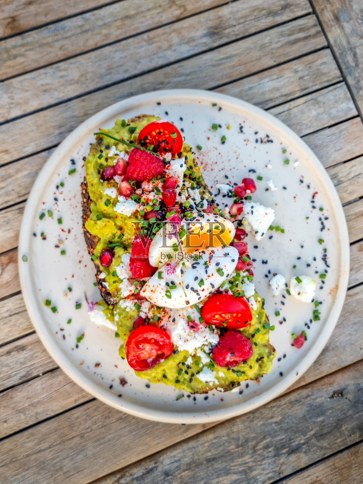 意式烤面包配牛油果和奶油奶酪，用浆果和花朵装饰，在海滩上享用照片摄影图片