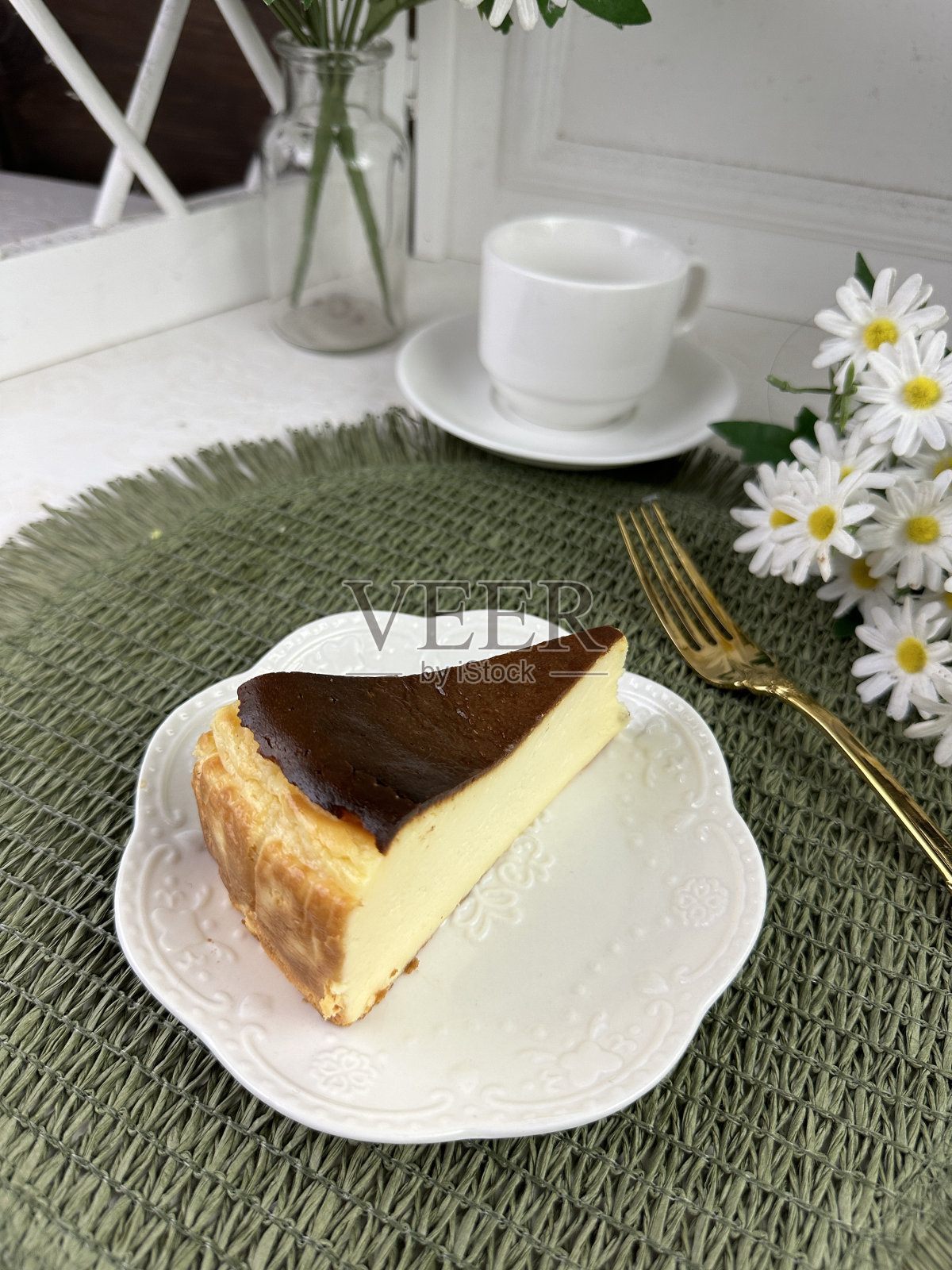 白色盘子里的巴斯克奶酪蛋糕加奶油。咖啡馆桌子上的一块蛋糕。甜点。新鲜出炉的自制食谱。照片摄影图片