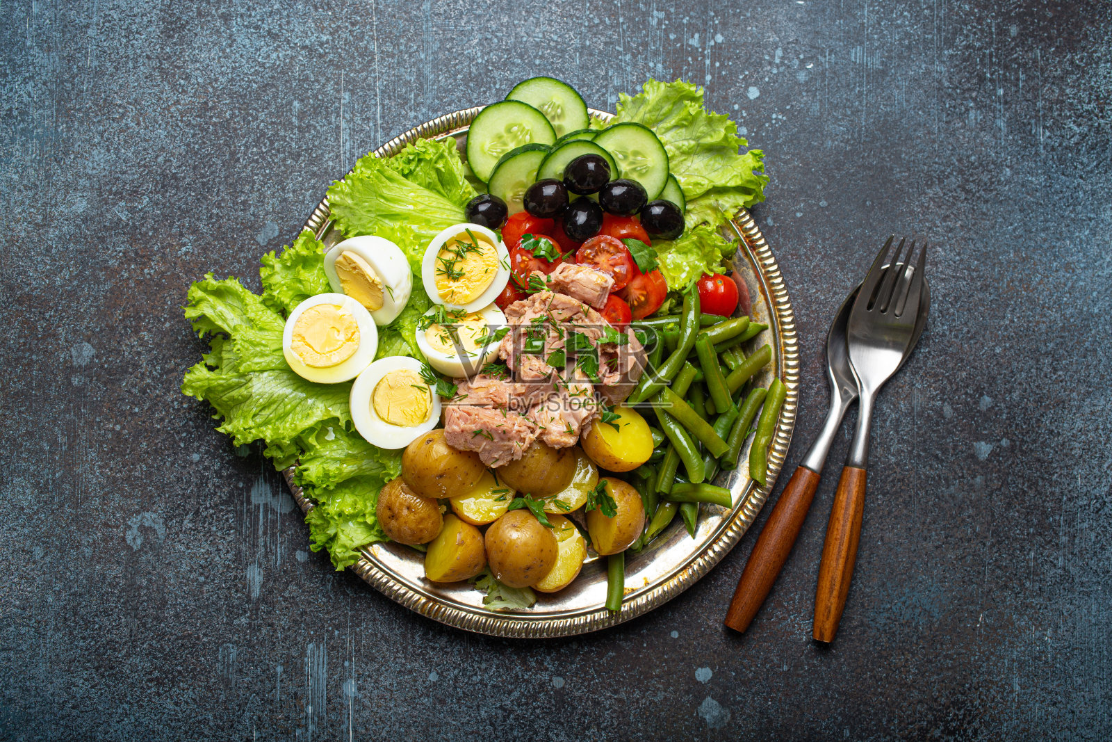 尼斯沙拉配金枪鱼、橄榄、青豆、西红柿和鹌鹑蛋，上面铺着生菜照片摄影图片