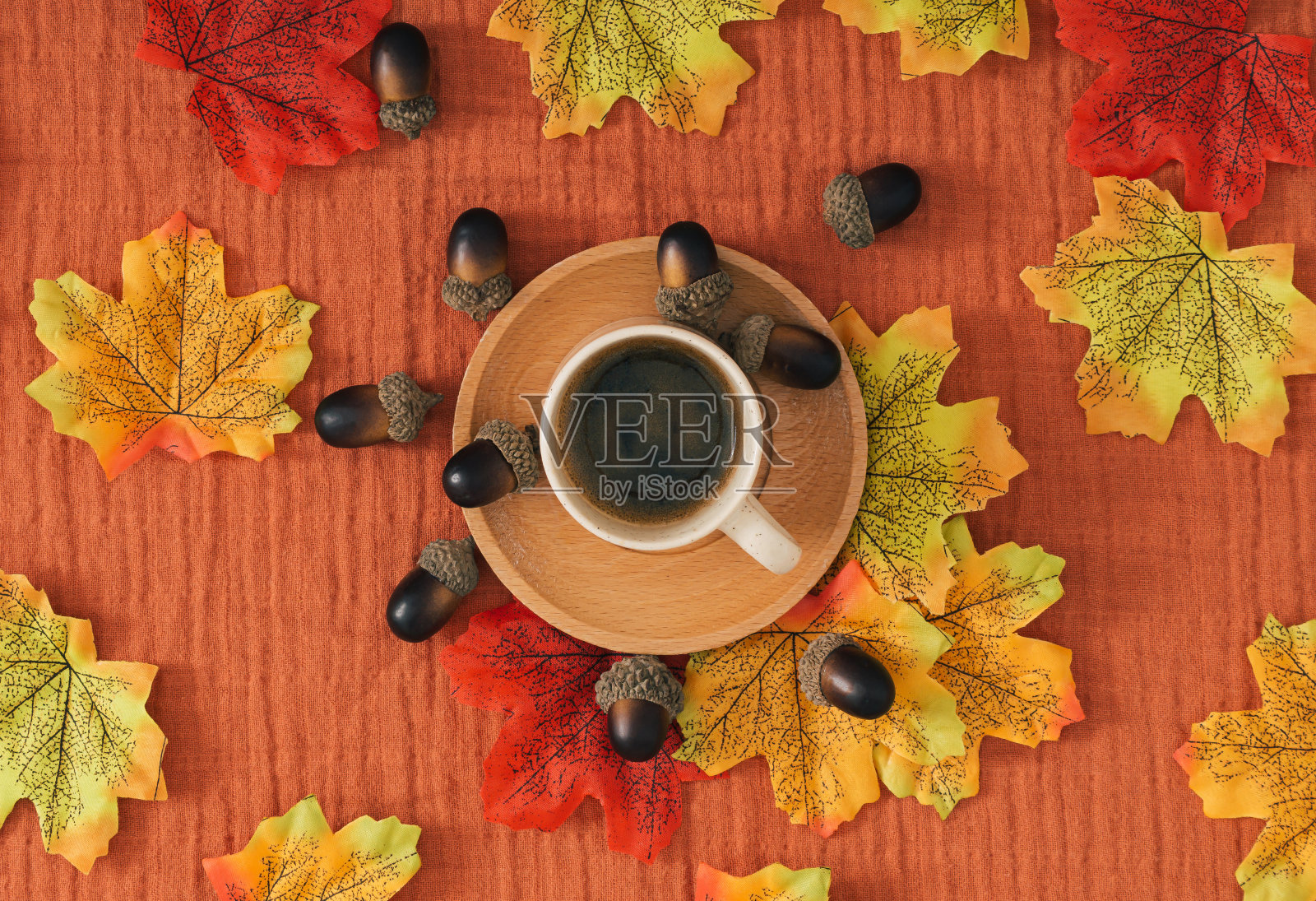 用秋天的树叶、坚果和一杯咖啡在棕色的薄纱背景上做成的五颜六色的秋天或秋天的图案。最小的季节概念。自然平地构成。照片摄影图片