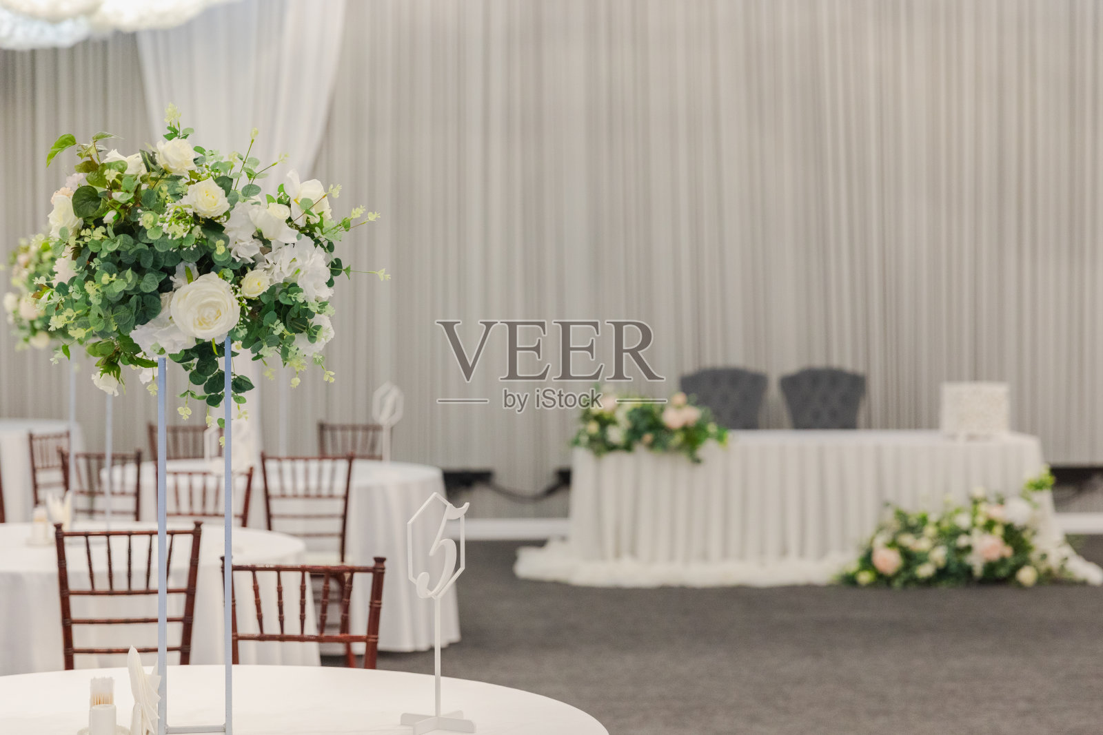 为节日活动而装饰的室内。花式餐桌设置晚餐与白色的花朵组成的餐厅，豪华的室内背景。婚宴装饰优雅，由餐饮服务安排。照片摄影图片