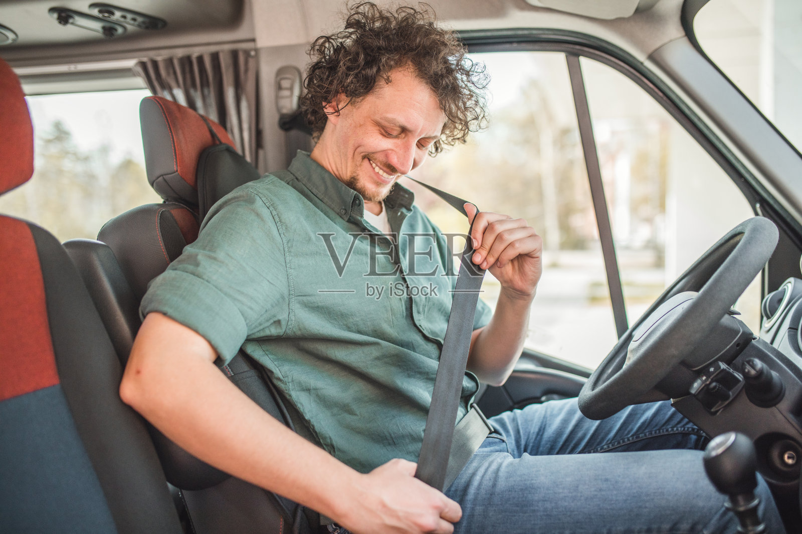 一位兴高采烈的巴士司机担心安全，在小巴旅程开始前系上了安全带照片摄影图片