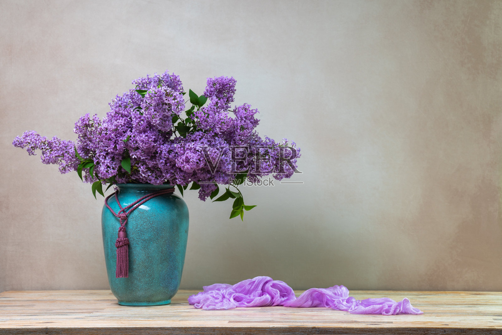 静物与一大束丁香花在一个大绿松石花瓶在浅色背景，与丁香披肩躺在旁边。本空间照片摄影图片