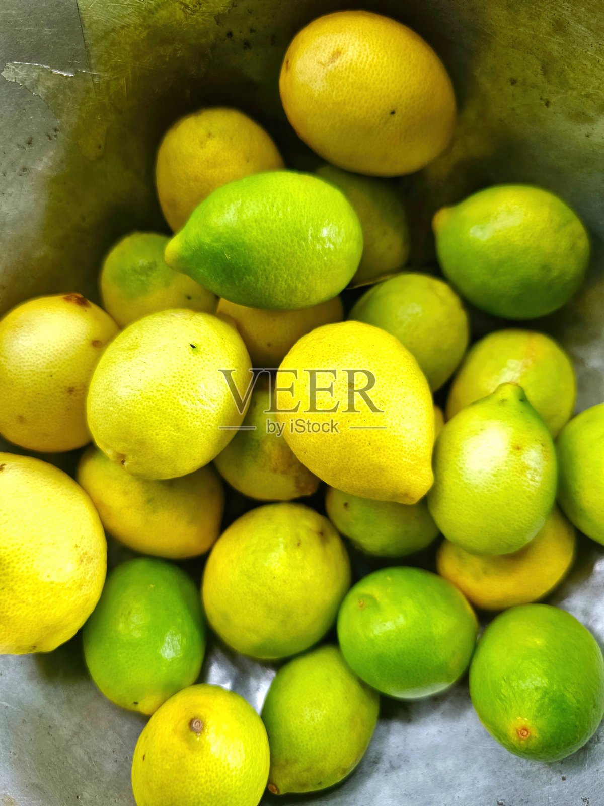 市场摊位上的金属碗里装着柠檬和酸橙。照片摄影图片