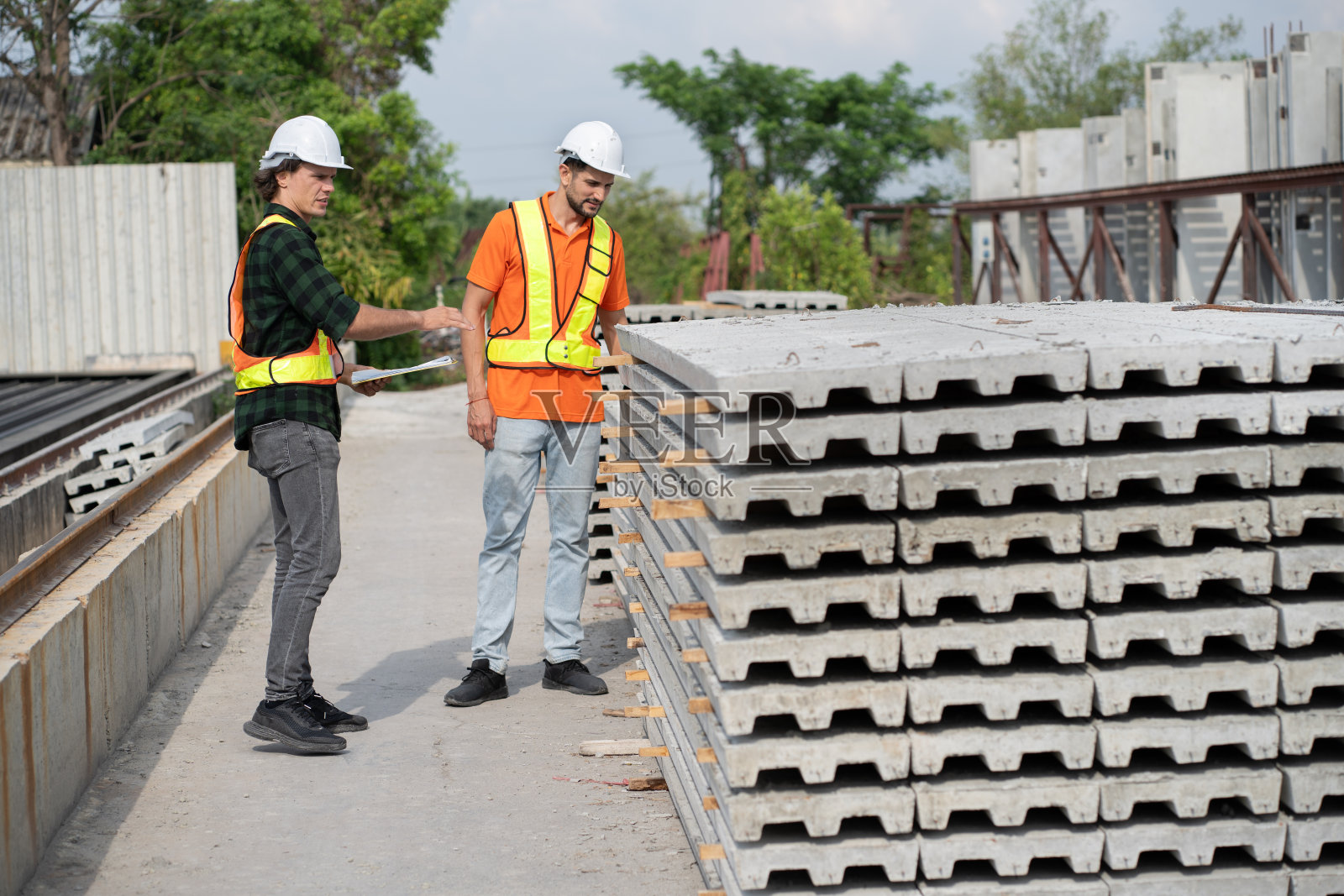 肖像白人工程师与西班牙裔拉丁工程师在预制水泥室外工厂工作照片摄影图片