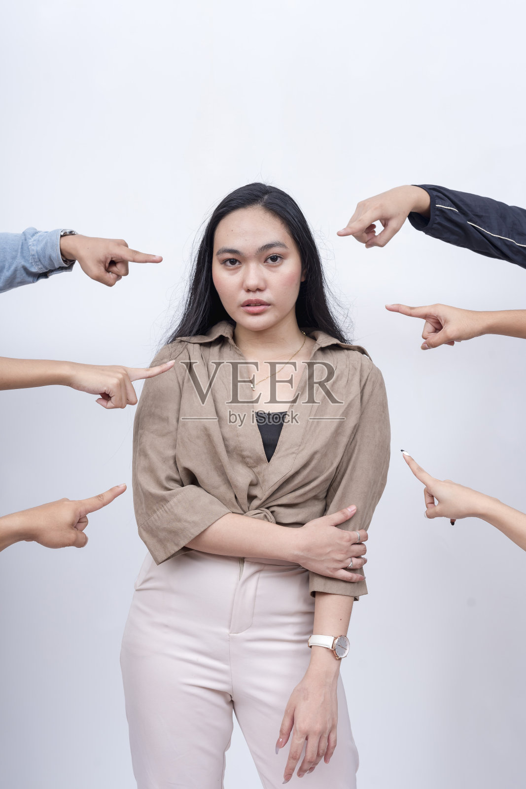 一个悲伤而不安的年轻女子被指责。无名之辈的手指着她。指控和审判的概念。舆论法庭。照片摄影图片