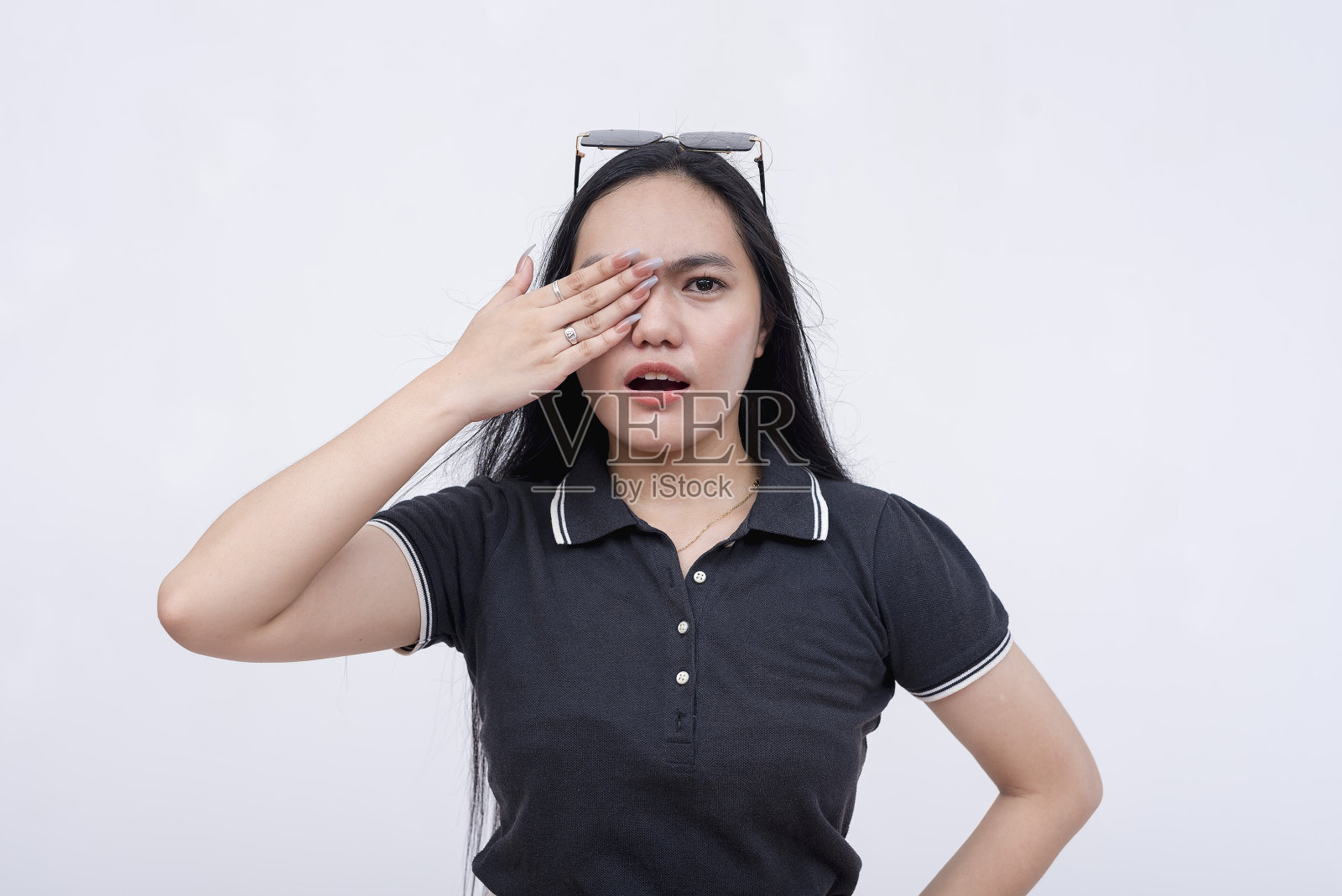 一个年轻女子捂着一只眼睛，感到有点震惊。穿着时髦的休闲装。孤立在白色背景上。照片摄影图片