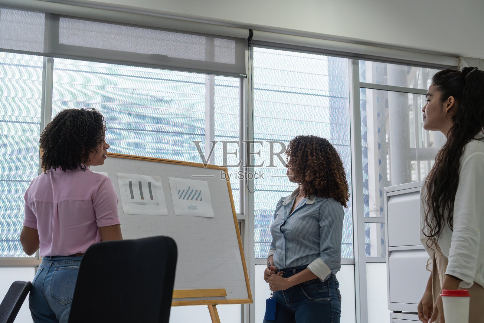 女性在现代办公室里分析白板上的图表照片摄影图片