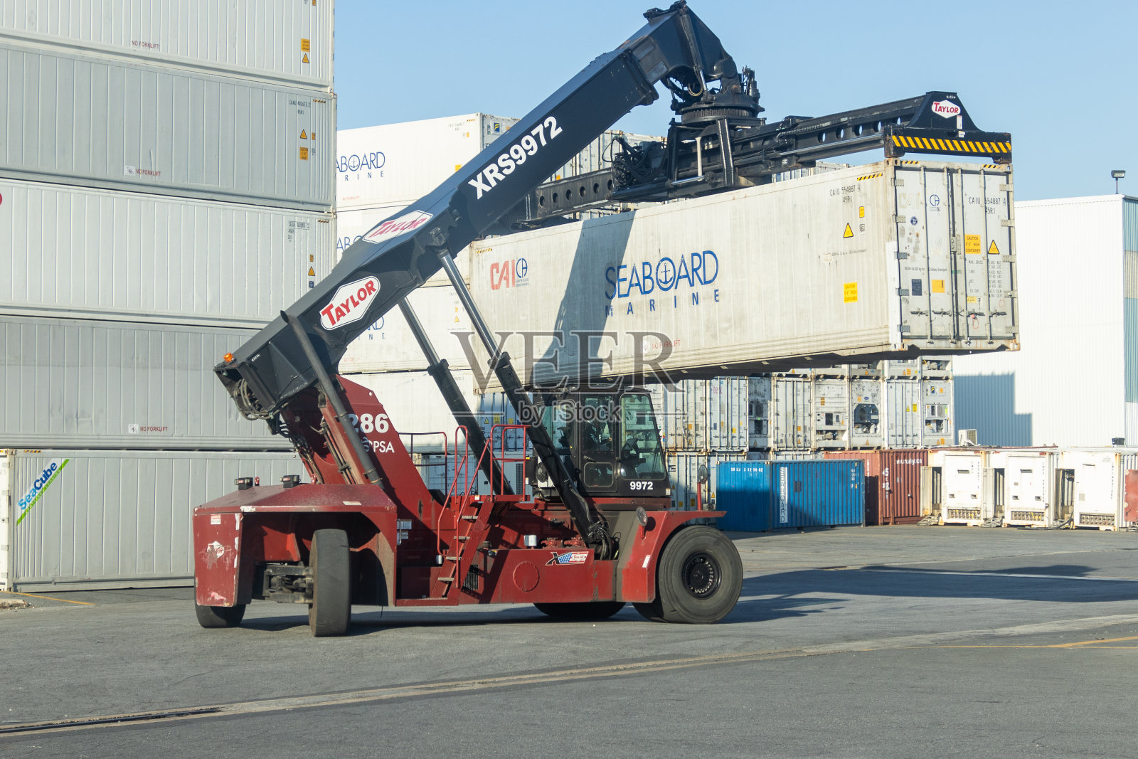 工业堆垛机在行动，有效地处理货物集装箱在繁忙的航运码头在白天。照片摄影图片