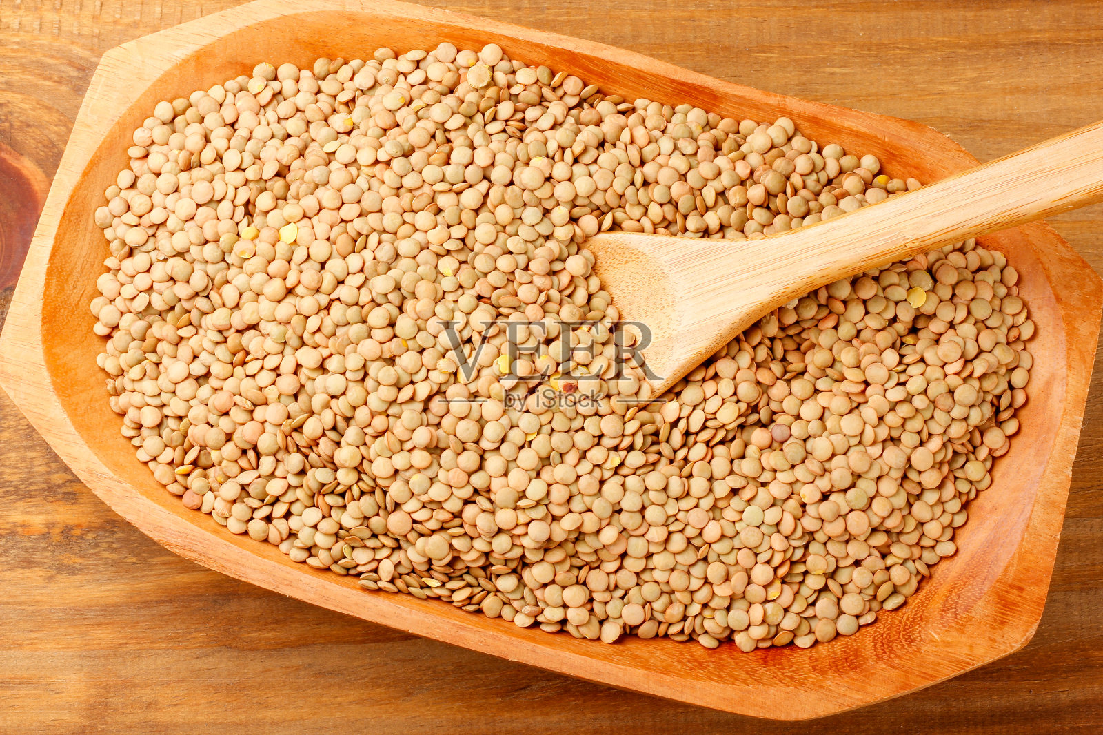 质朴的木桌上，木碗里盛着棕色的生干扁豆照片摄影图片