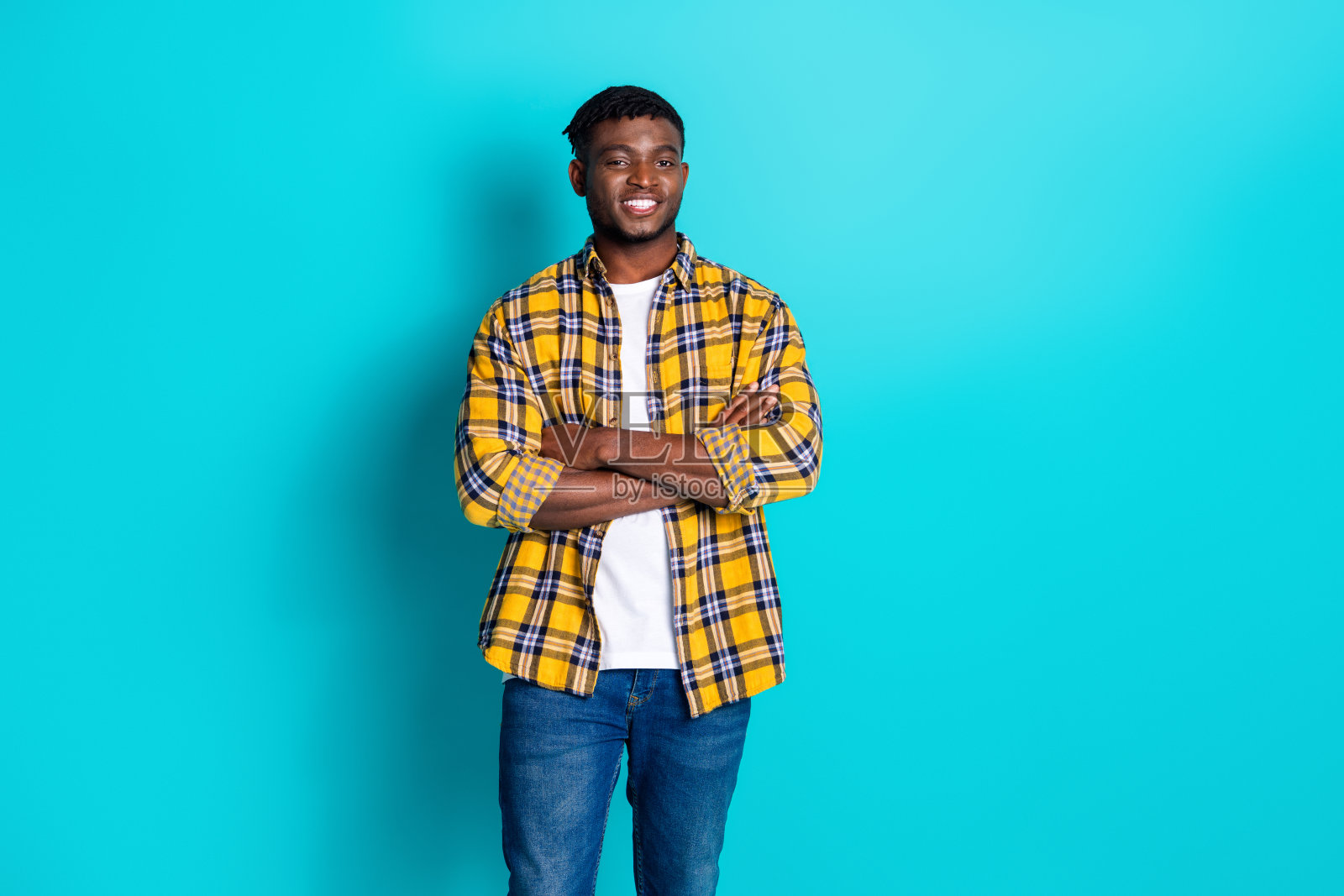 照片中，英俊迷人的男子穿着时髦的格纹衣服，双臂交叉在青色背景上照片摄影图片