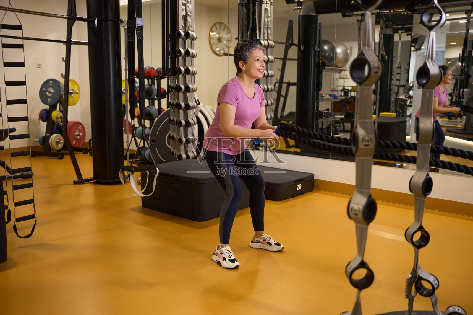 一位面带微笑的中年白人妇女在健身房用绳子做运动照片摄影图片