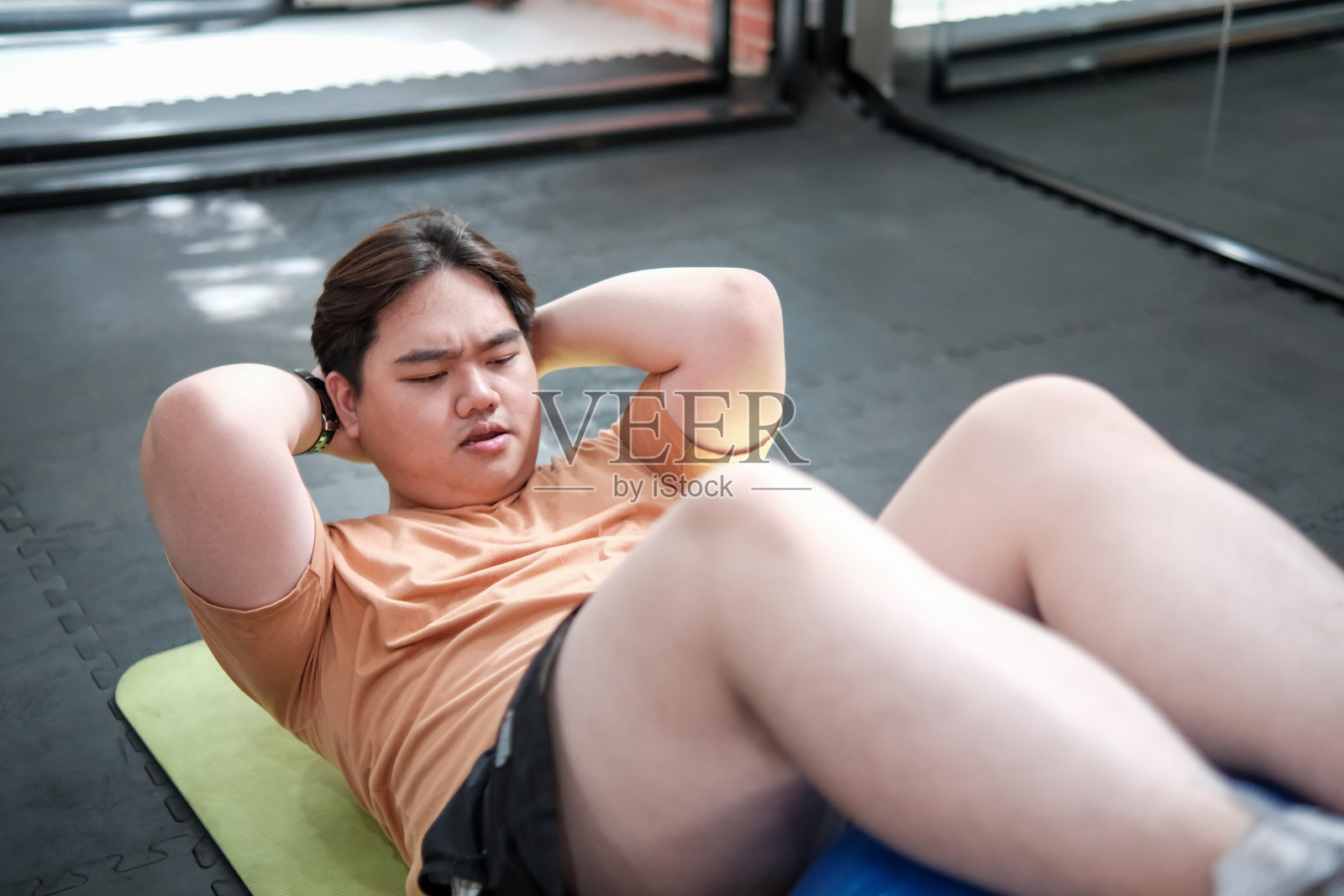 超重男子在运动垫上做仰卧起坐照片摄影图片
