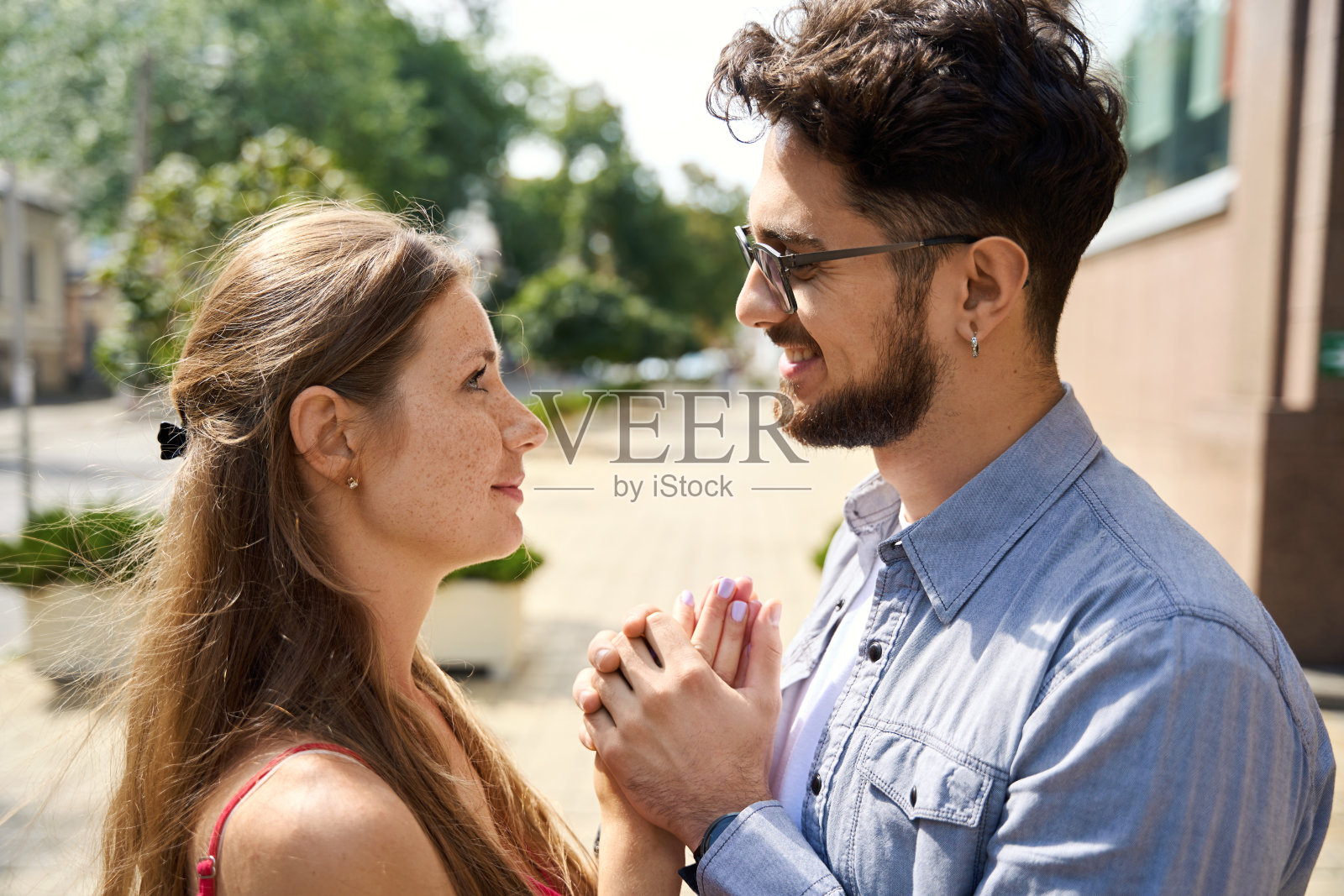 年轻幸福的夫妇手牵着手，看着对方裁剪侧视图照片摄影图片