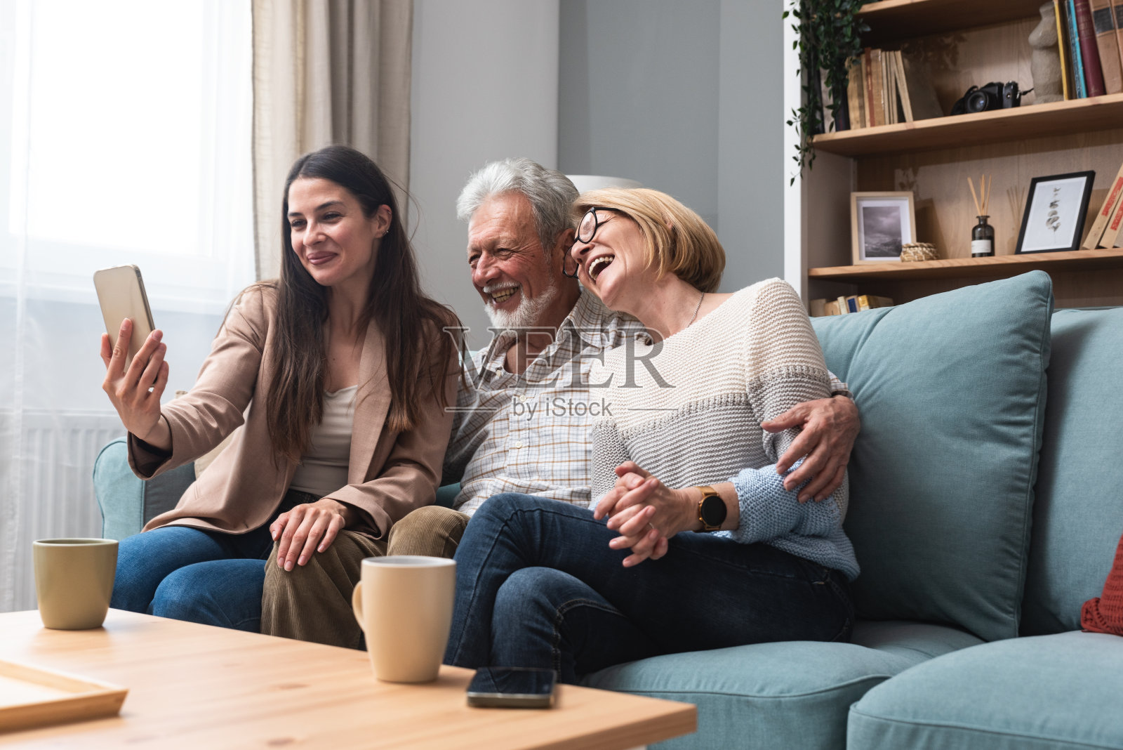 简单的生活母亲，父亲和女儿在家里享受美好的时光。老夫妇和年轻女子在公寓客厅聊天，在看望父母的周末活动中玩得很开心照片摄影图片