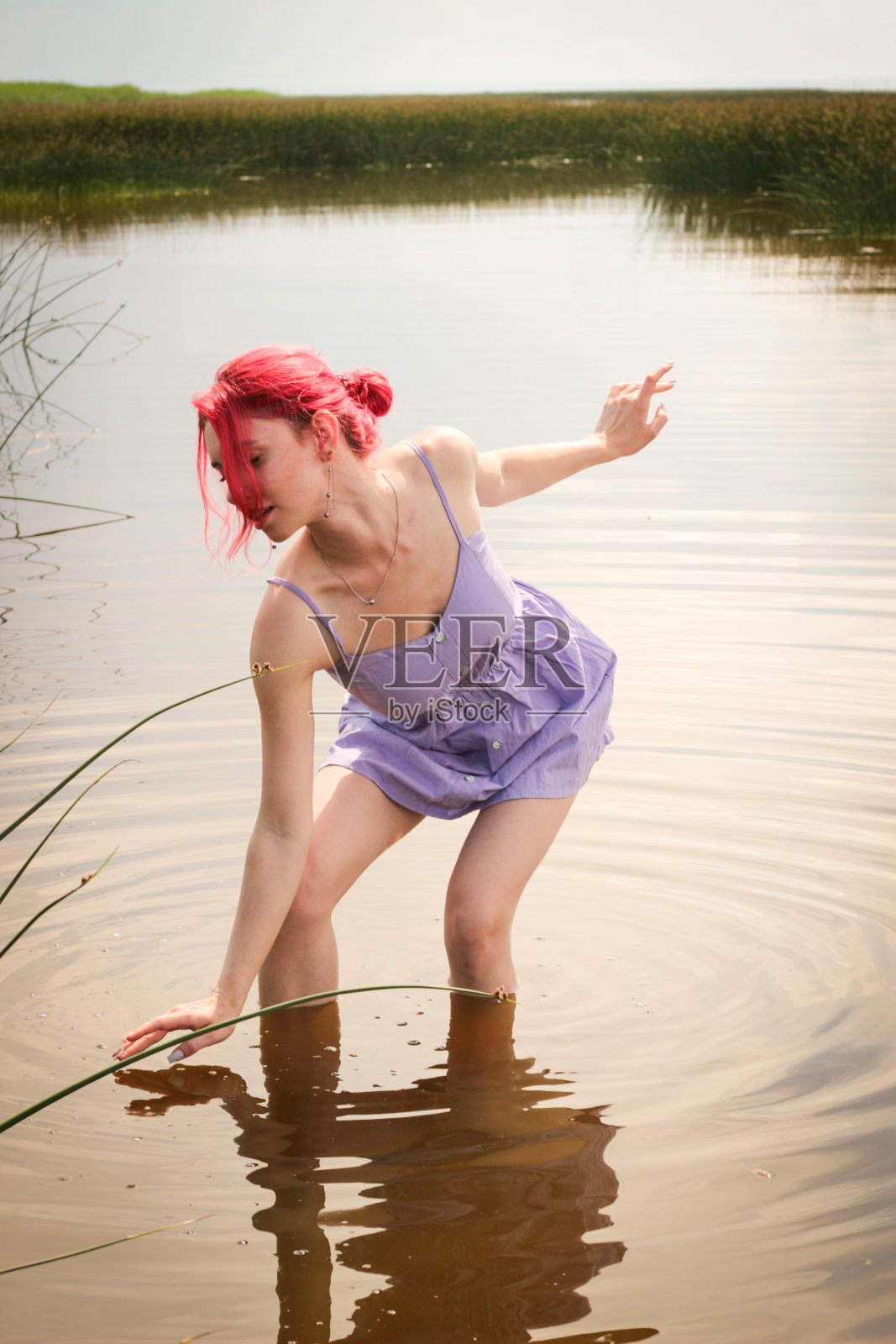 穿着裙子的漂亮女孩在水中以自然为背景摆姿势。高质量照片照片摄影图片