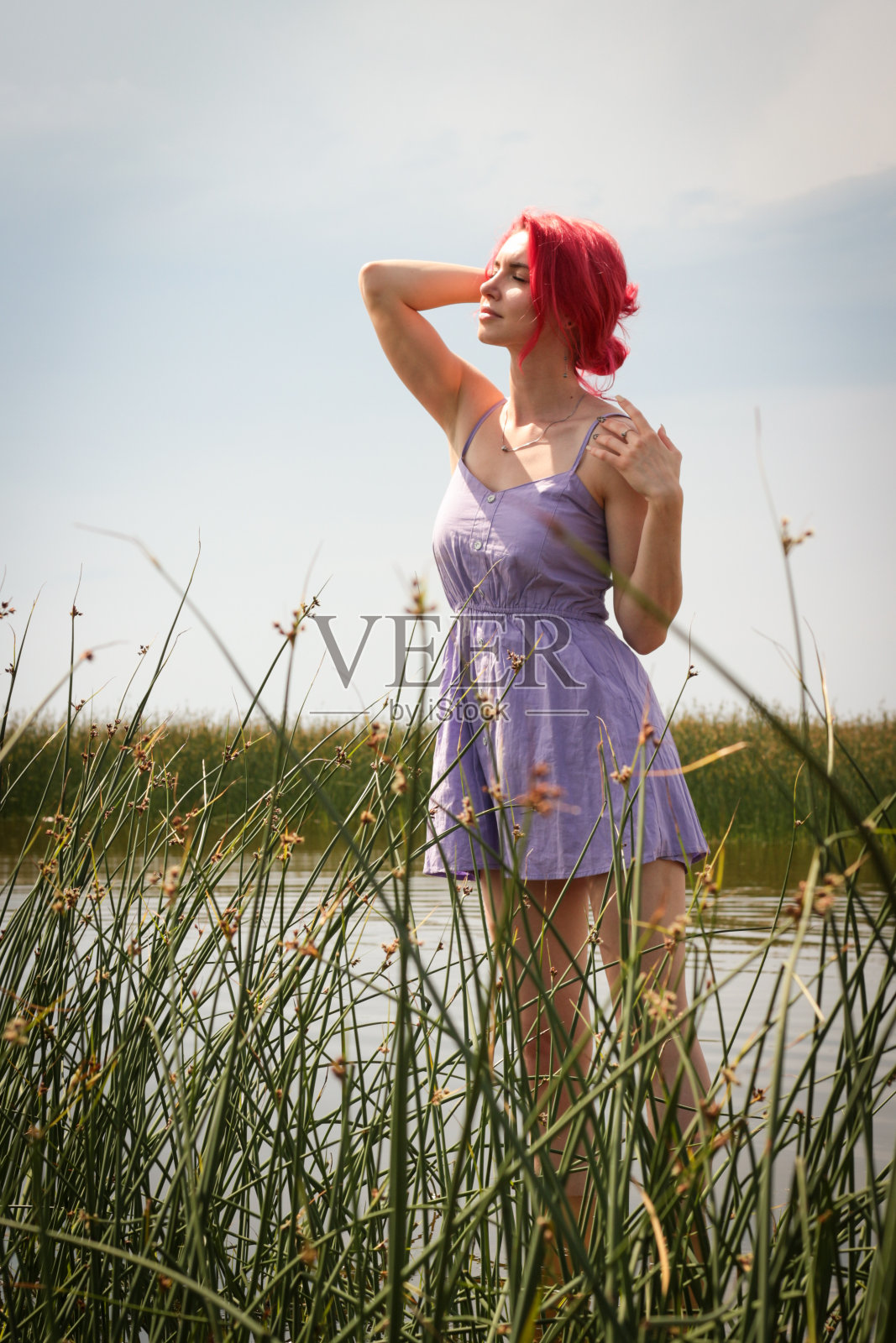 穿着裙子的漂亮女孩在水中以自然为背景摆姿势。高质量照片照片摄影图片