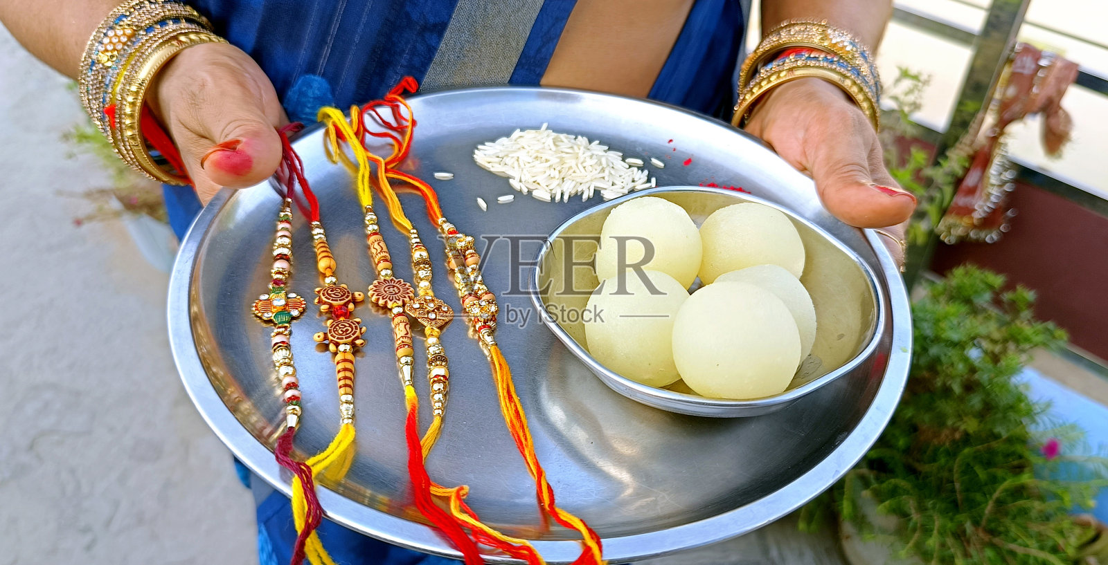 印度姐姐在Raksha Bandhan的场合拿着一盘rakhi和糖果照片摄影图片