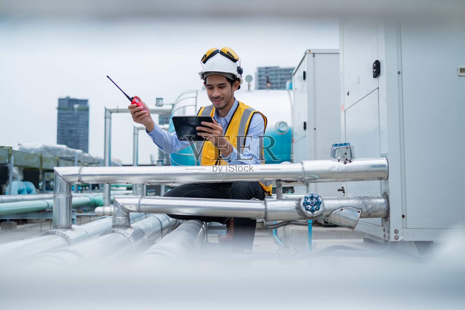 工程师检查工业屋顶的热水器泵系统和热水箱照片摄影图片