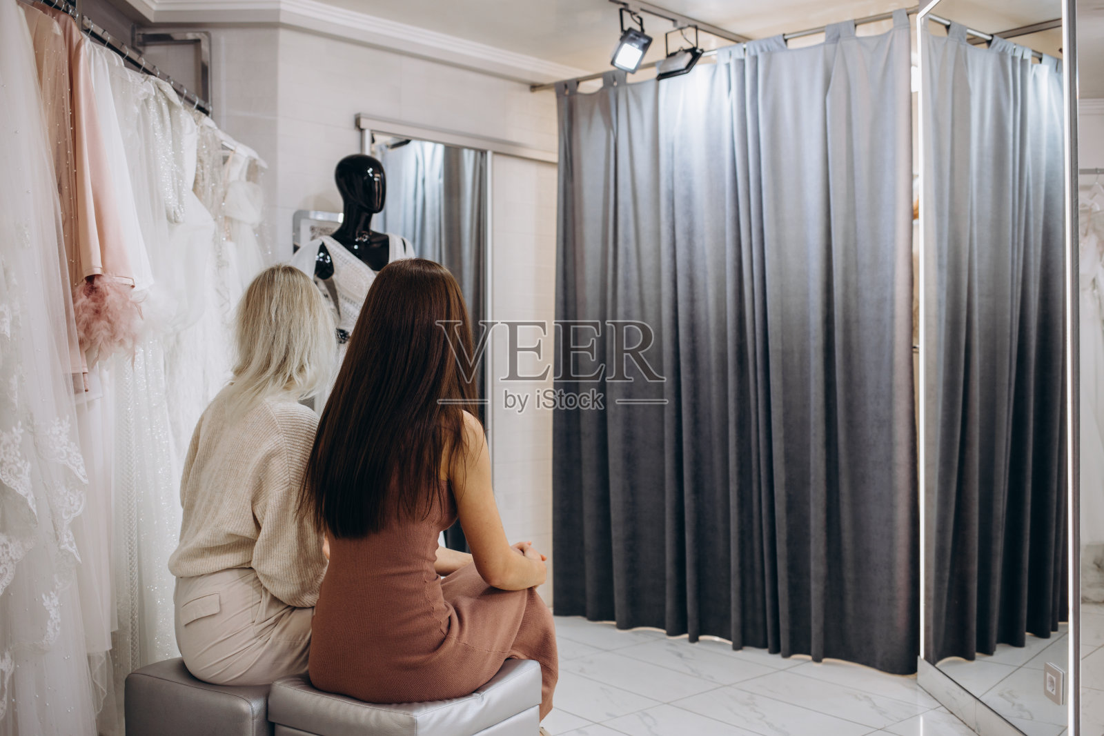 在现代的婚礼沙龙里，年轻迷人的新娘微笑着选择婚纱，女孩们展示了更多的礼服照片摄影图片