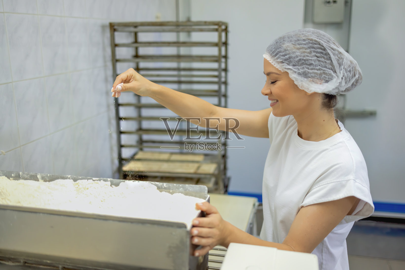 面包师在商业面包店往生面团中加入面粉照片摄影图片