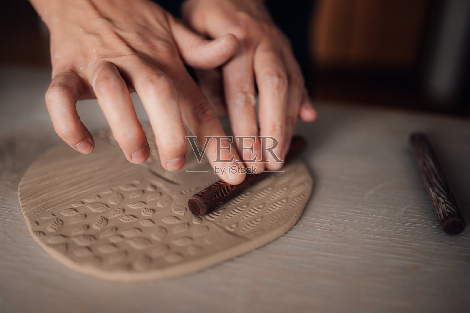 近距离的手用小擀面杖湿粘土装饰。照片摄影图片