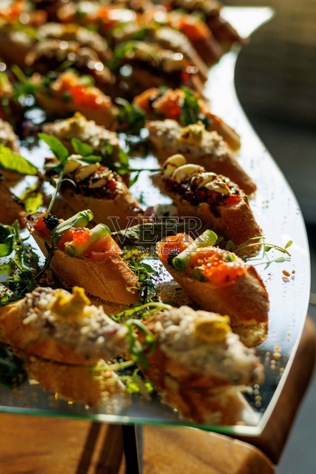 一个充满活力的阵列美食意式烤面包顶部与新鲜的食材在玻璃服务托盘。照片摄影图片