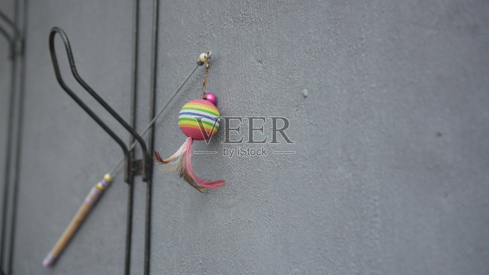 棍子玩具，一端是彩色的球，另一端是红色和棕色的鸡毛照片摄影图片