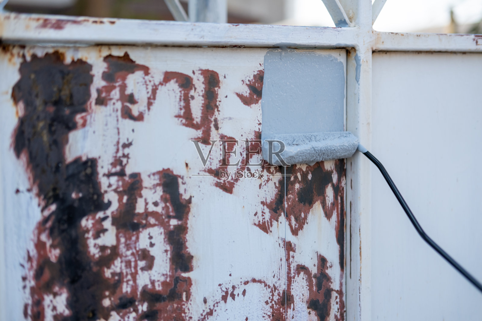 防锈底漆辊，涂在生锈的金属面板上照片摄影图片