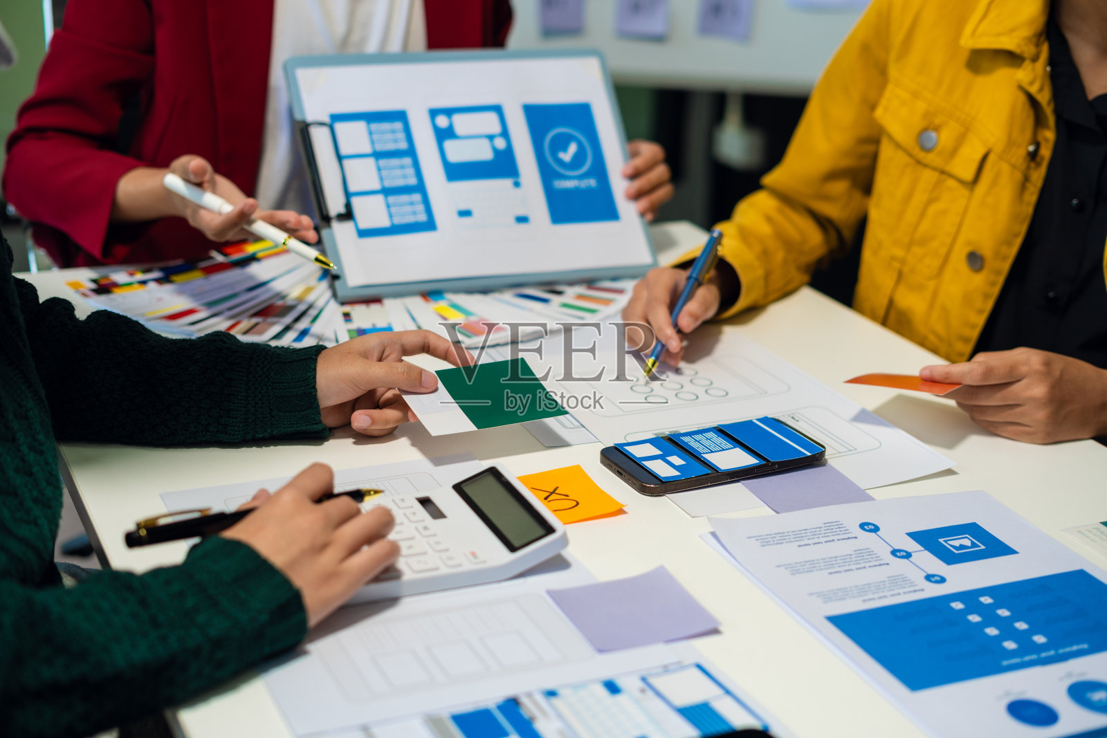 用户体验开发人员和ui设计师集思广益，设计手机应用程序界面线框图与客户简要和颜色代码，用户体验概念。照片摄影图片