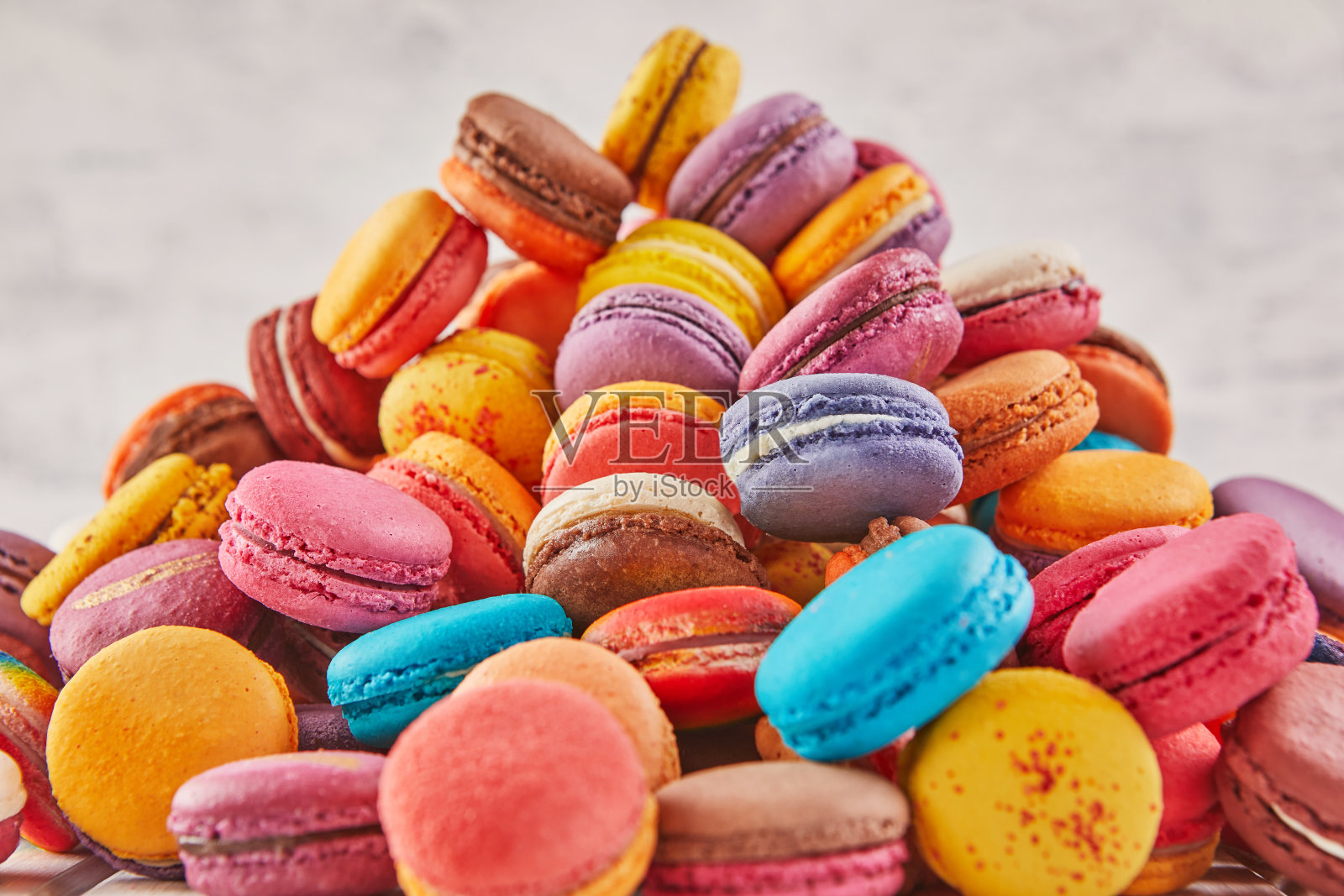 浅色木质背景上堆放着各种颜色的马卡龙照片摄影图片