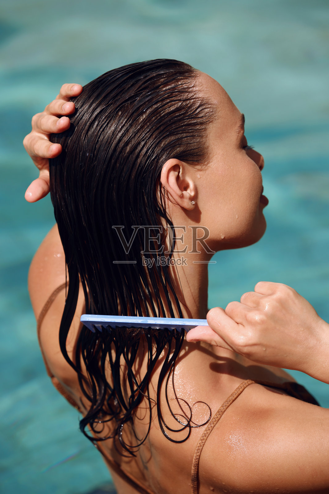 刷头发。美丽的年轻女子在长而湿的头发上敷上清爽的面膜照片摄影图片