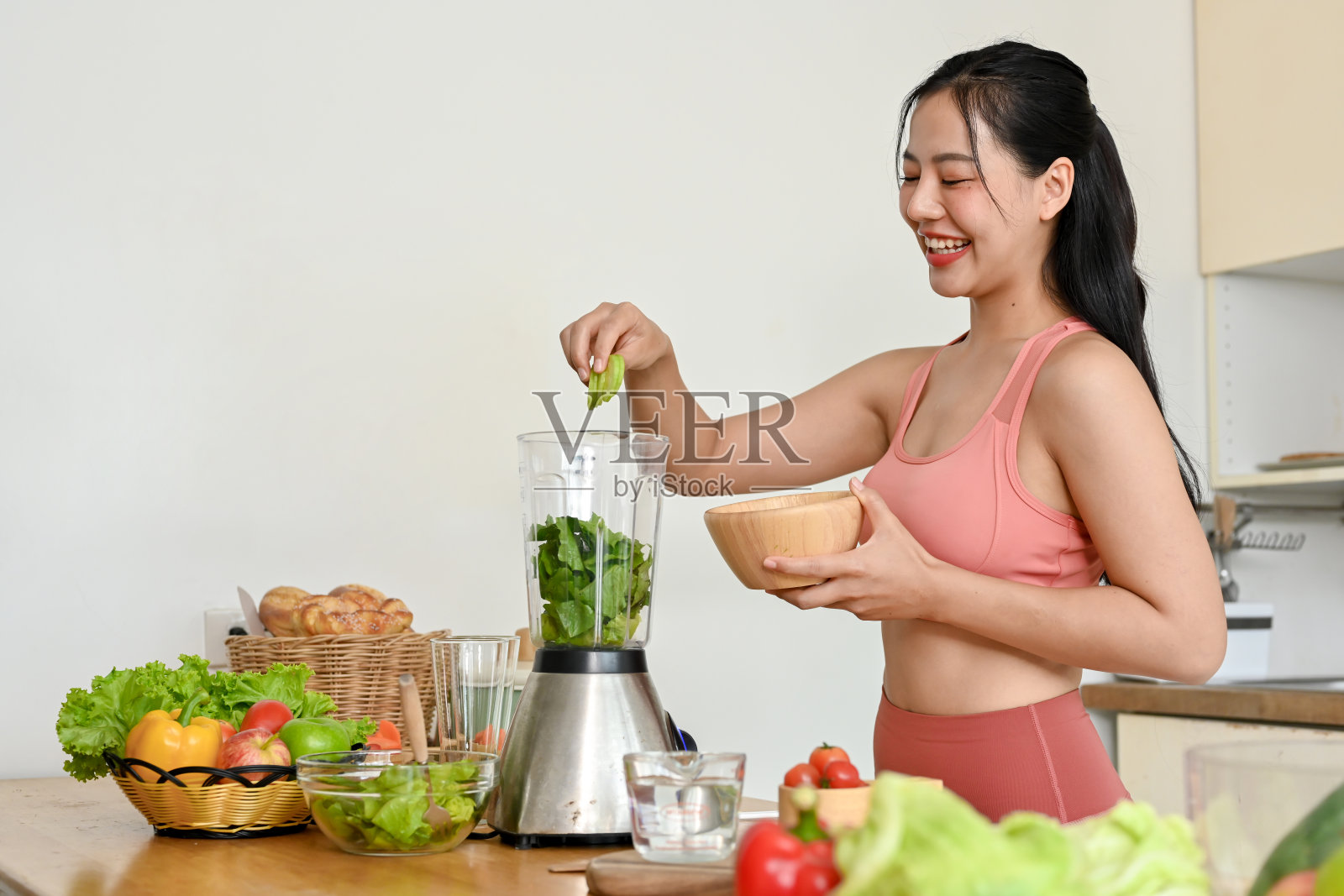 年轻女子在厨房用新鲜蔬菜制作冰沙。照片摄影图片