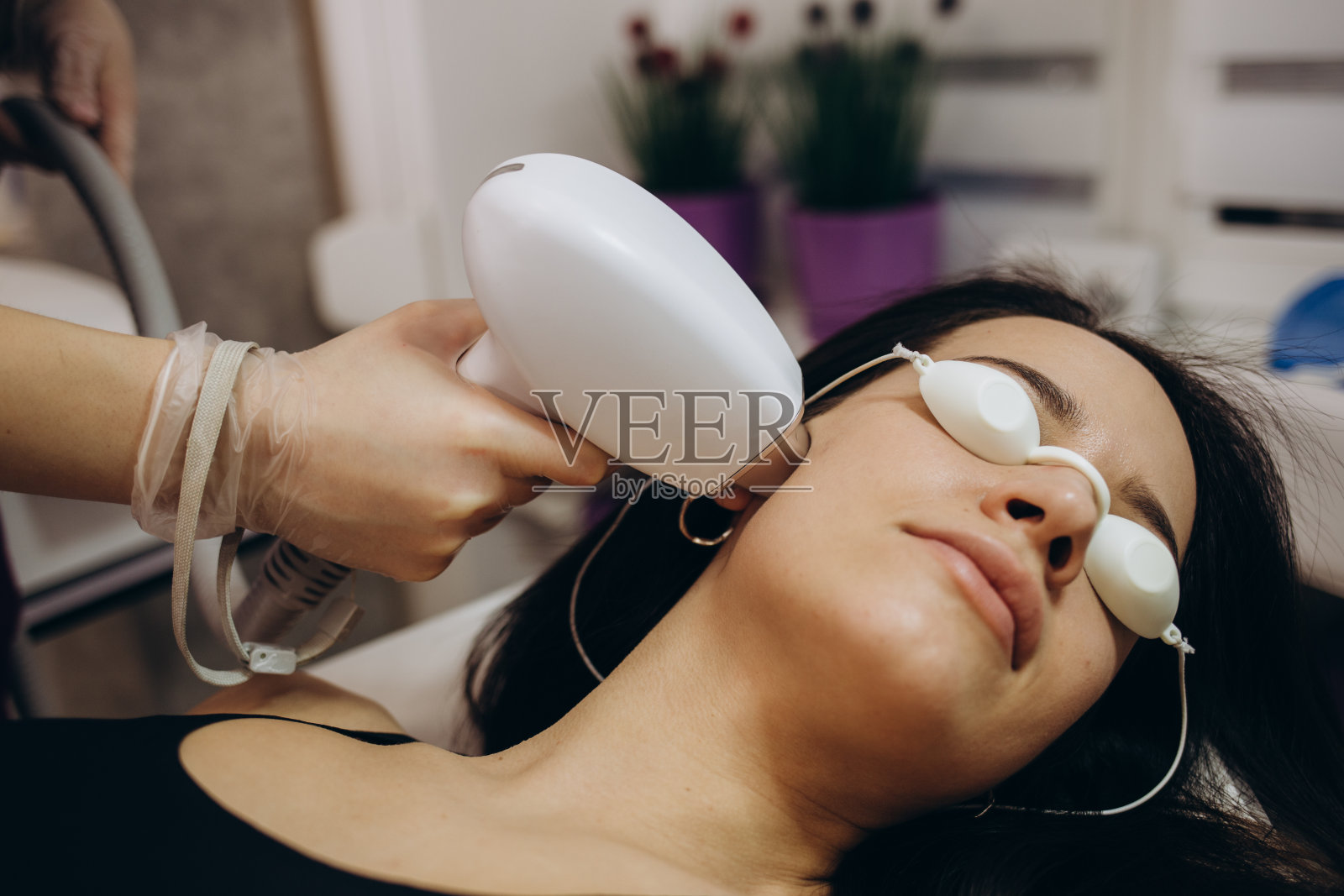 Elos脱毛脱毛程序在一个女人的脸上。美容院的美容师正在给颈部做激光恢复活力。面部皮肤护理。硬件ipl美容照片摄影图片