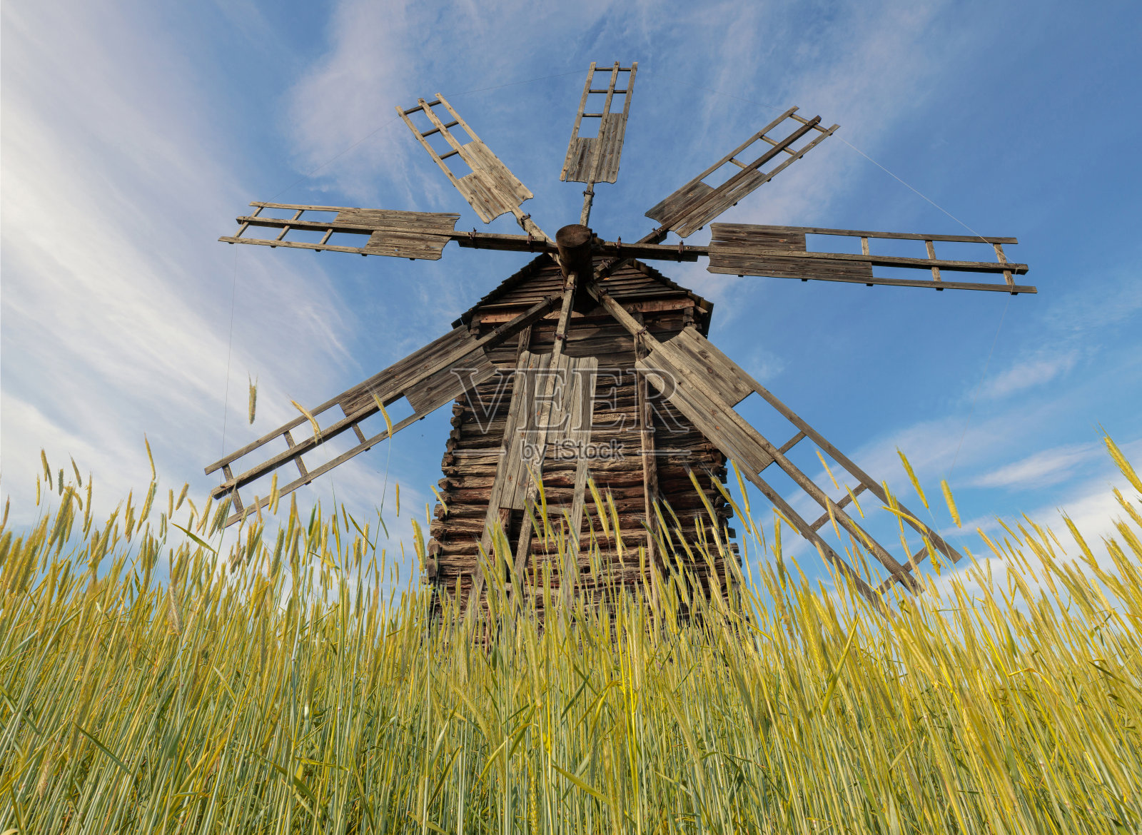 蓝天白云下黑麦地里古老的乡村风车。低角度视图。照片摄影图片