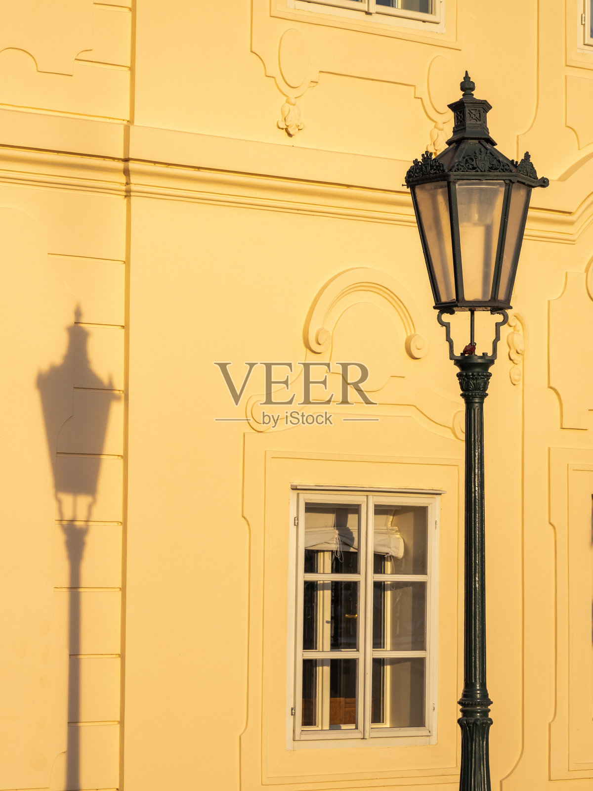 一盏古老的路灯和它在立面上的影子。照片摄影图片